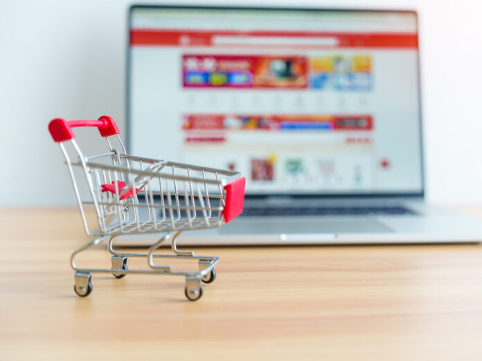 Carrinho de compras e laptop com site de mercado. conceito de negócios, tecnologia, comércio eletrônico, banco digital e pagamento on-line